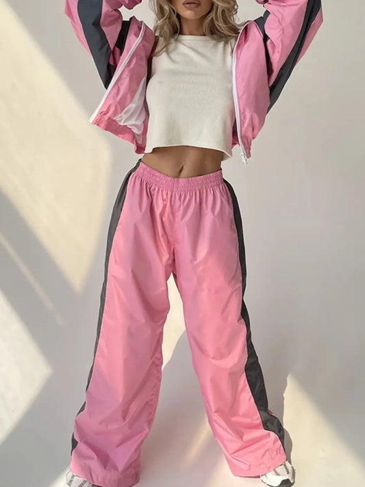 Person wearing a pink and black tracksuit with a white top against a neutral background