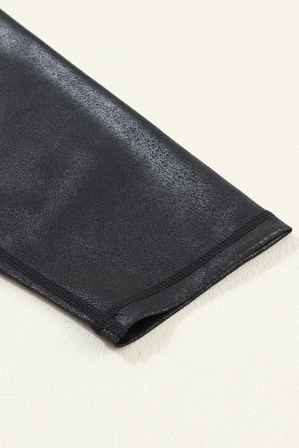Black leather glove on a light beige background