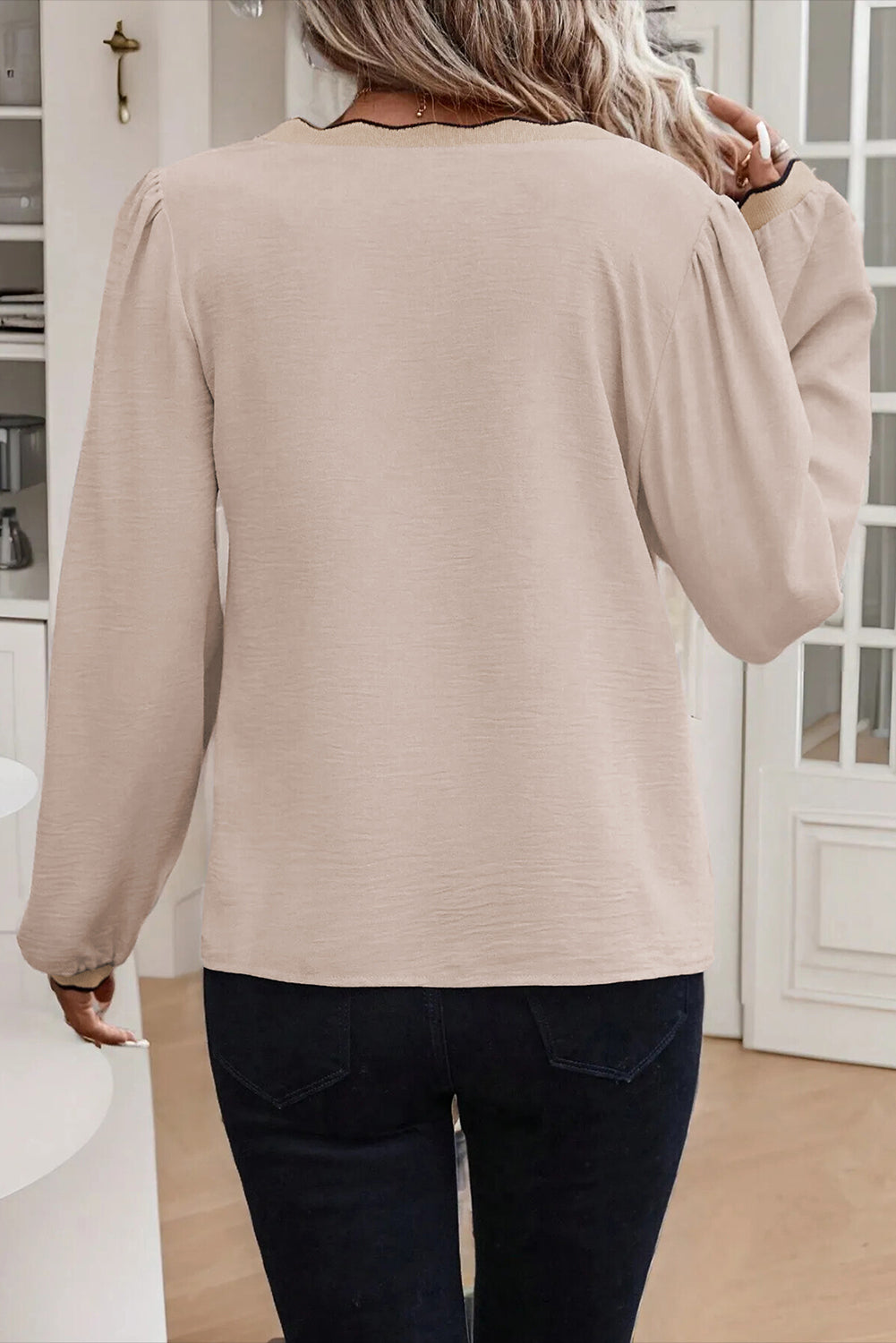 Person wearing a beige cardigan and dark pants in an indoor setting