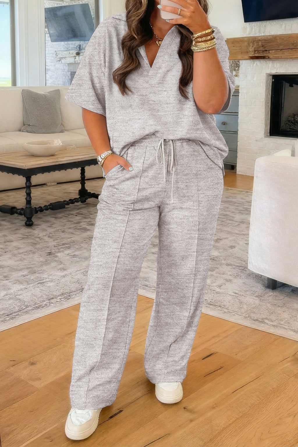 Woman wearing a gray lounge set in a living room.