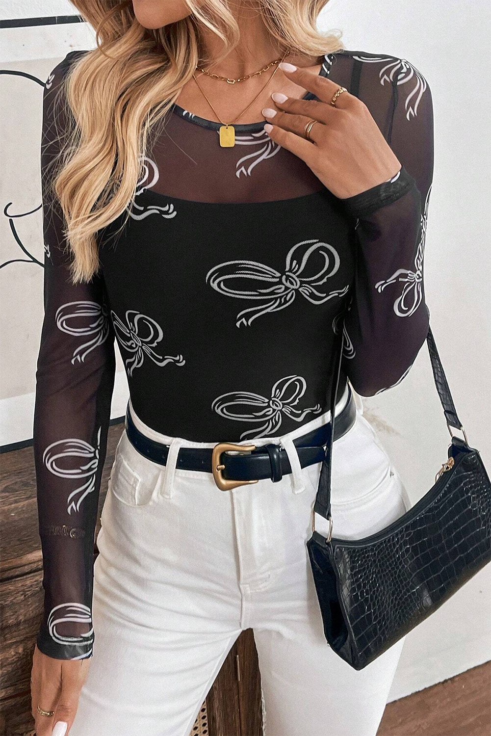 Person wearing a black long-sleeve top with white bow patterns and white pants.