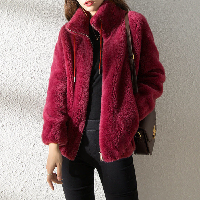 Person wearing a burgundy fur coat against a neutral background