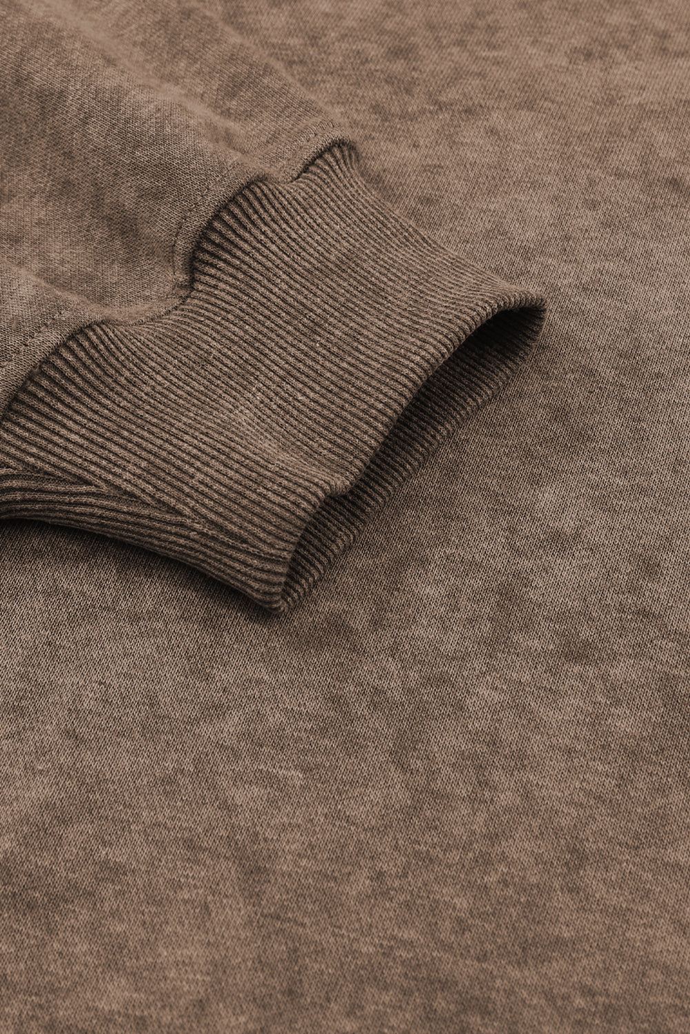Close-up of a brown sweater sleeve on a matching brown fabric background