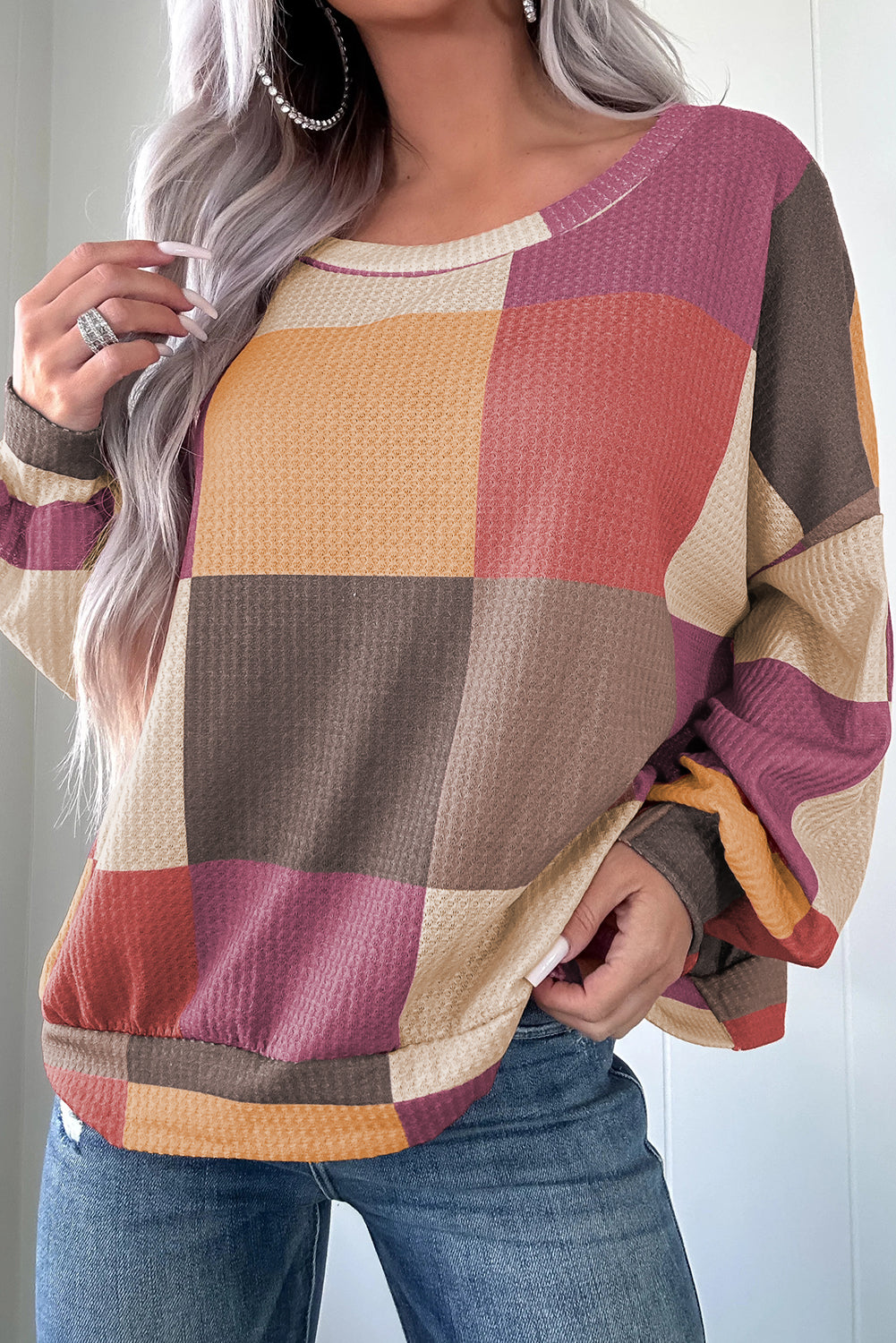 Person wearing a colorful checkered sweater with a neutral background