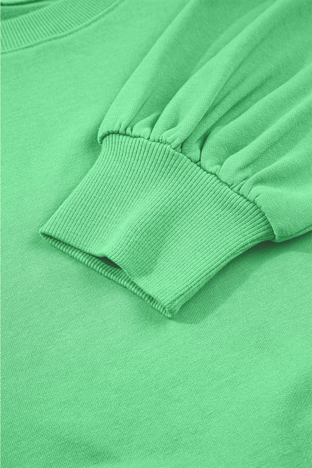 Close-up of a green sweatshirt with a focus on the sleeve and collar.