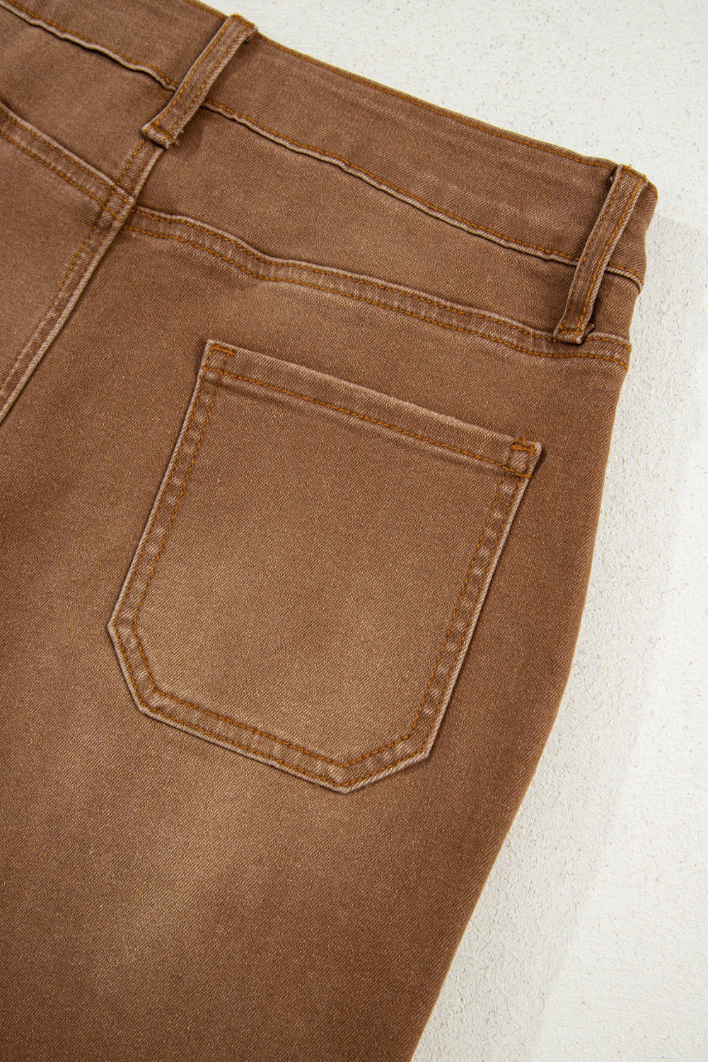 Close-up of brown pants with a pocket on a light background