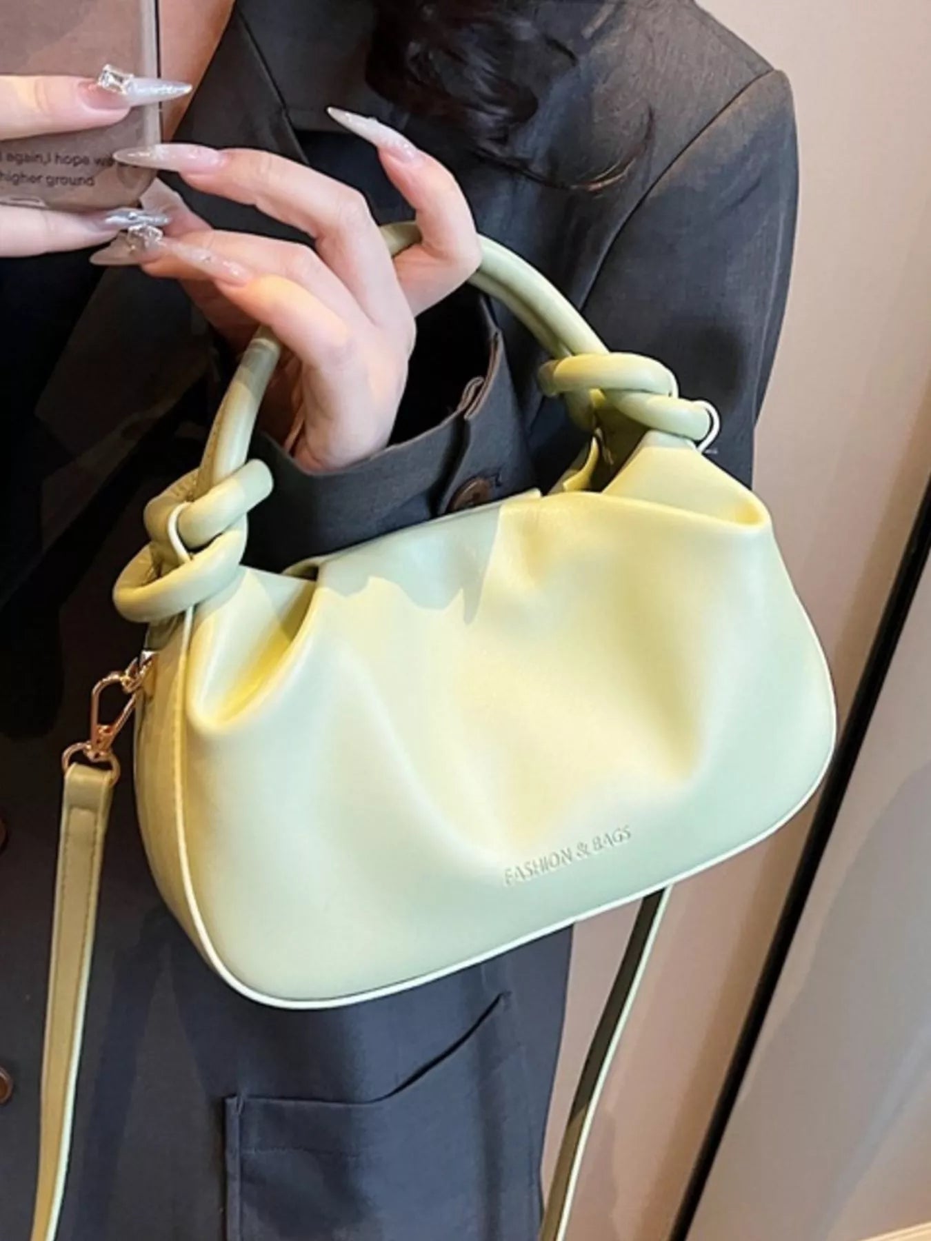 Person holding a light green handbag with a plain background