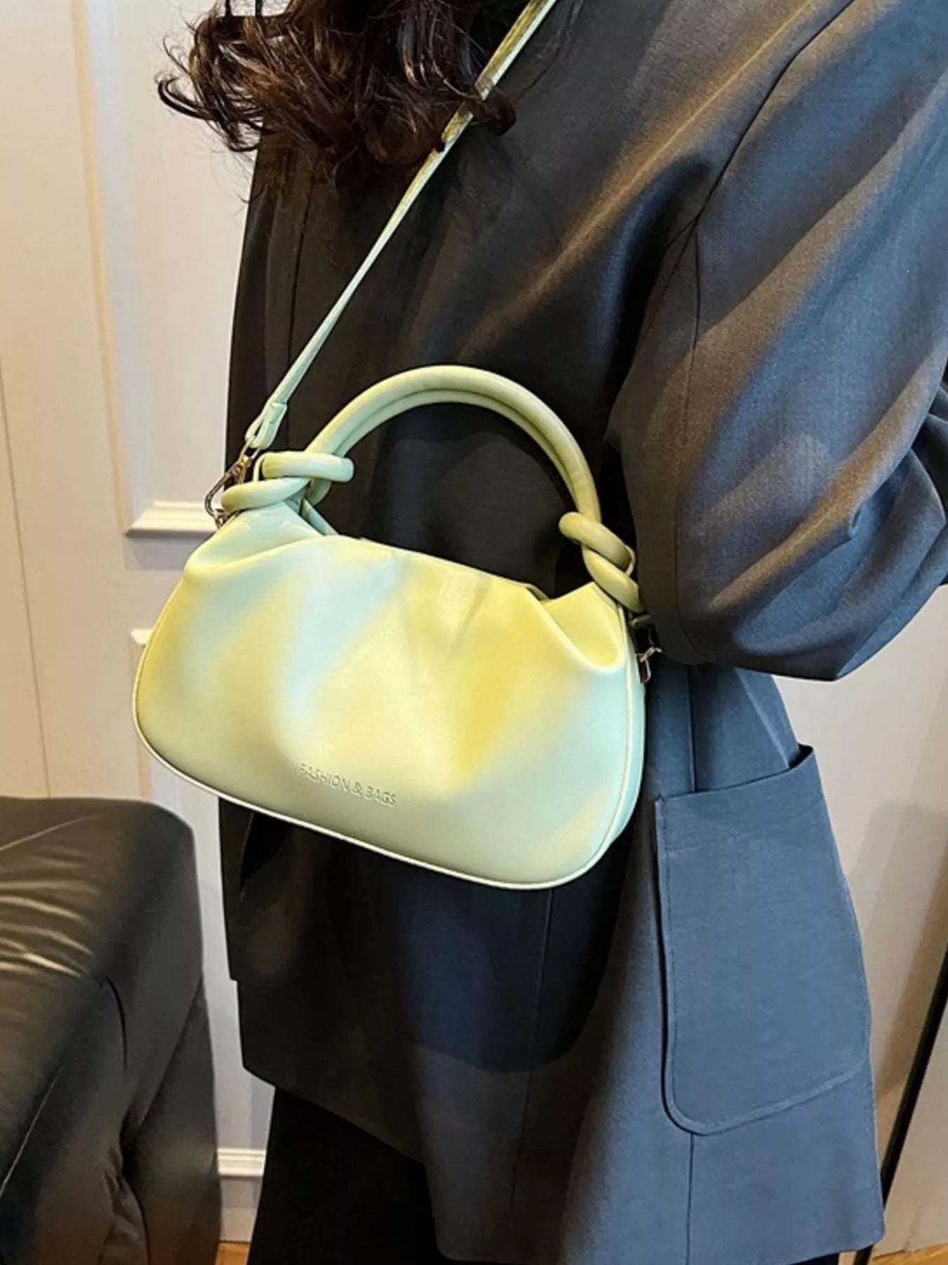 Person holding a light green handbag with a blurred background