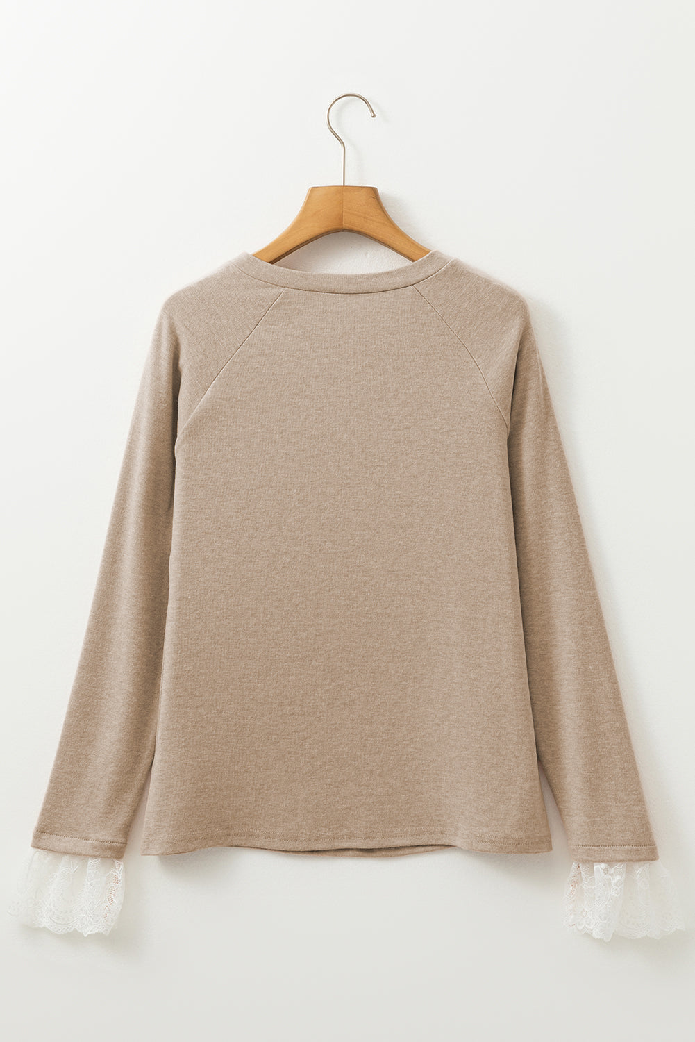 Beige long-sleeve shirt on a wooden hanger against a white background