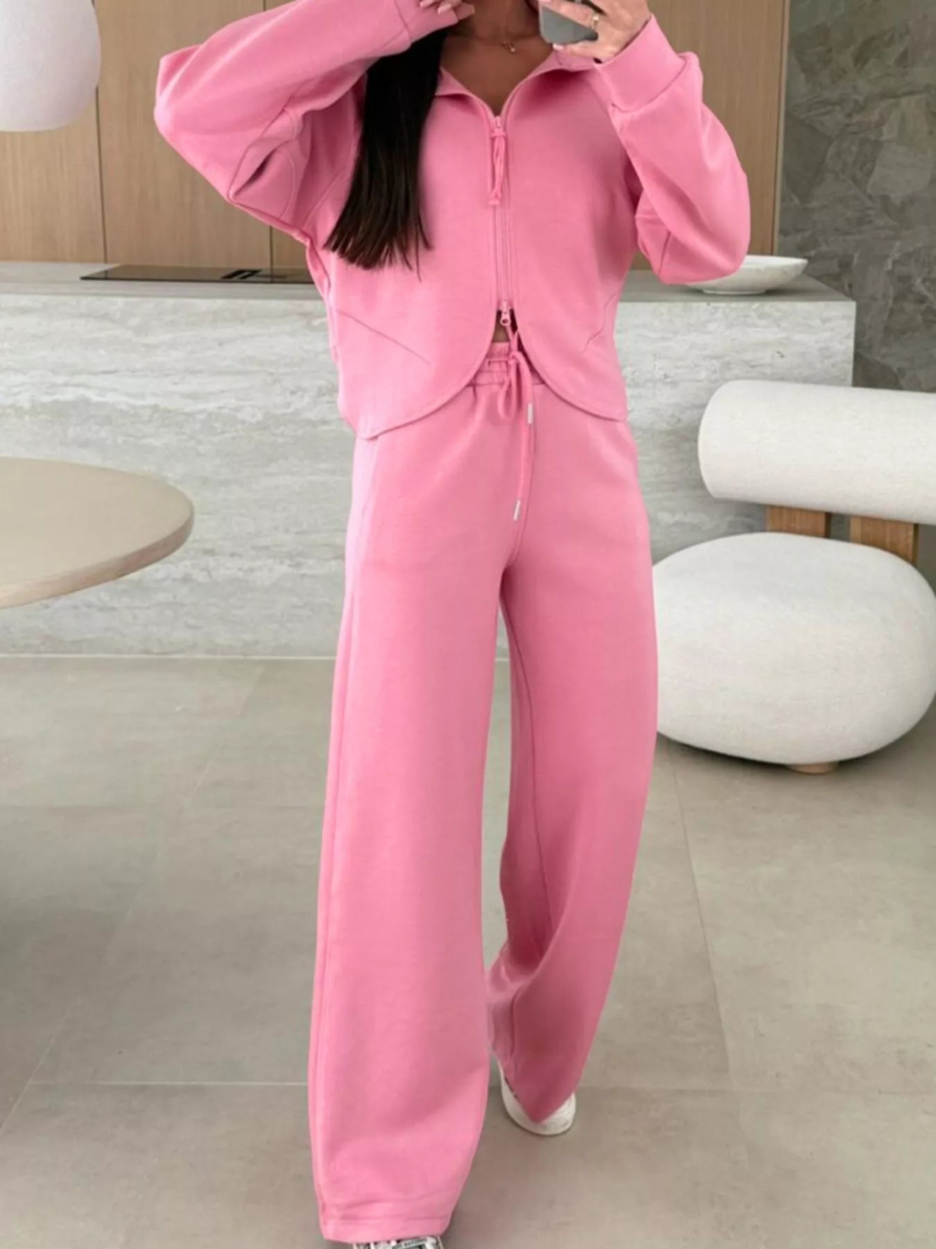 Person wearing a pink tracksuit in a modern indoor setting