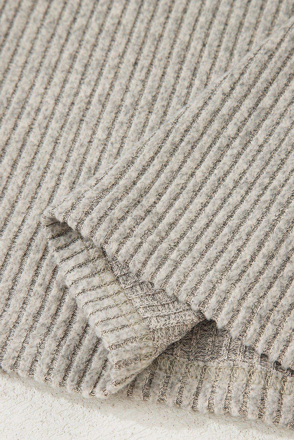 Close-up of a textured beige fabric with a ribbed pattern.