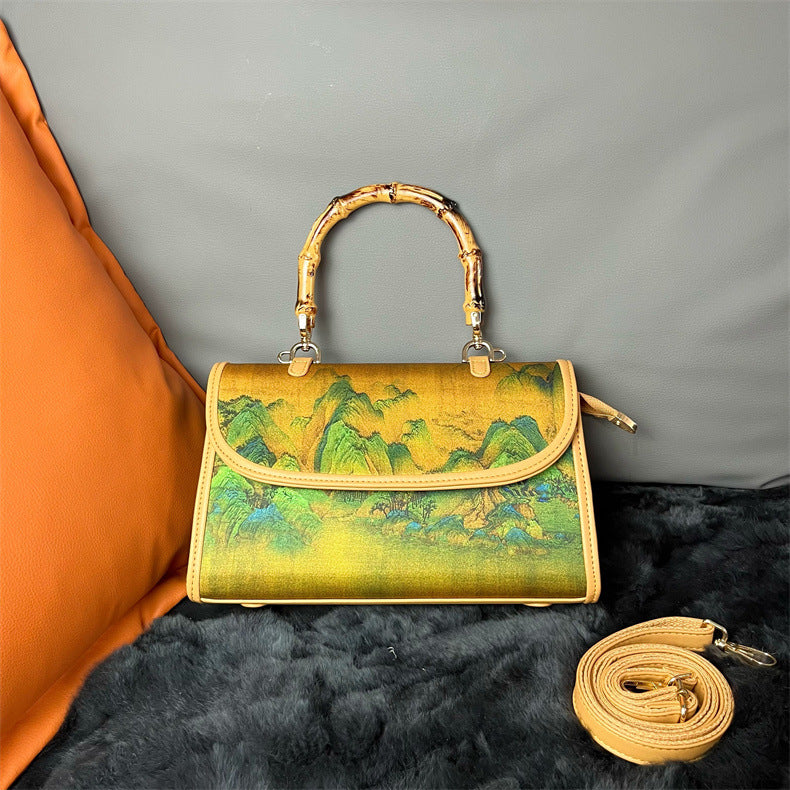 Handbag with bamboo handle and scenic design on a textured surface
