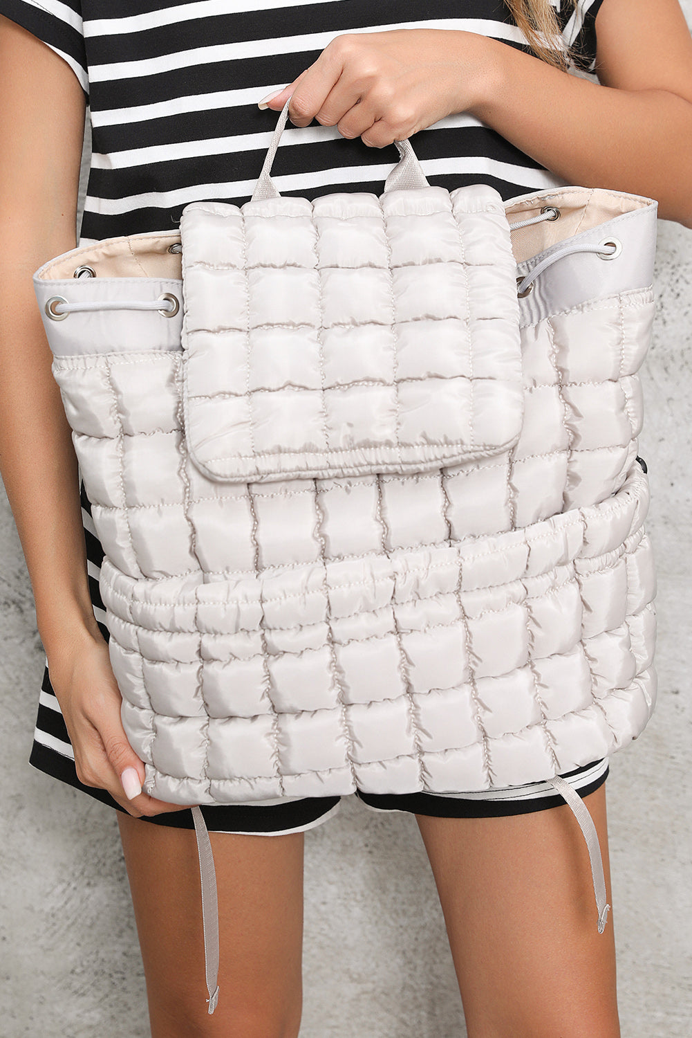 Model holding a Chic medium grey Quilted Puffer Flap Backpack 