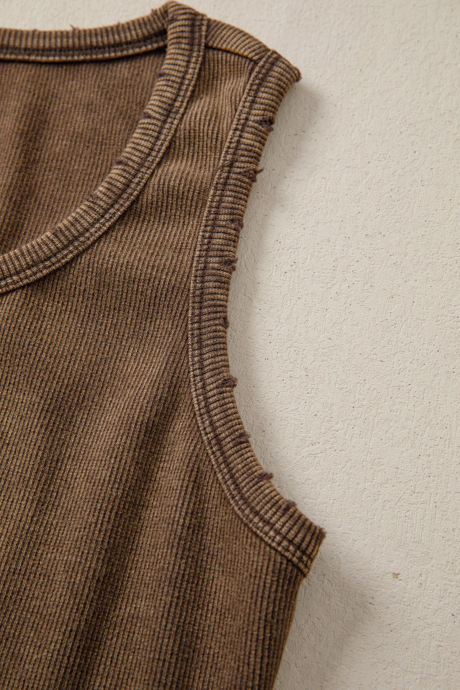Brown ribbed sleeveless garment on a beige background