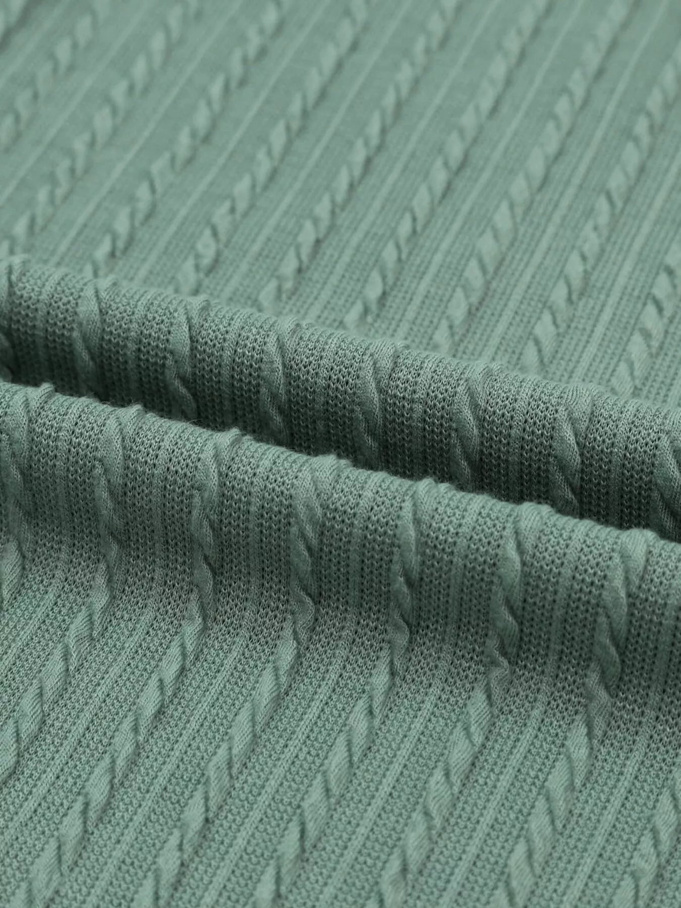 Close-up of textured green fabric with cable knit pattern