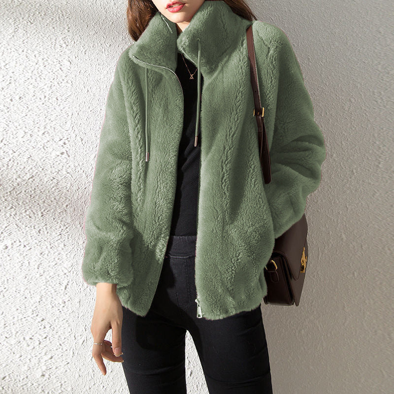 Person wearing a green textured jacket with a plain background