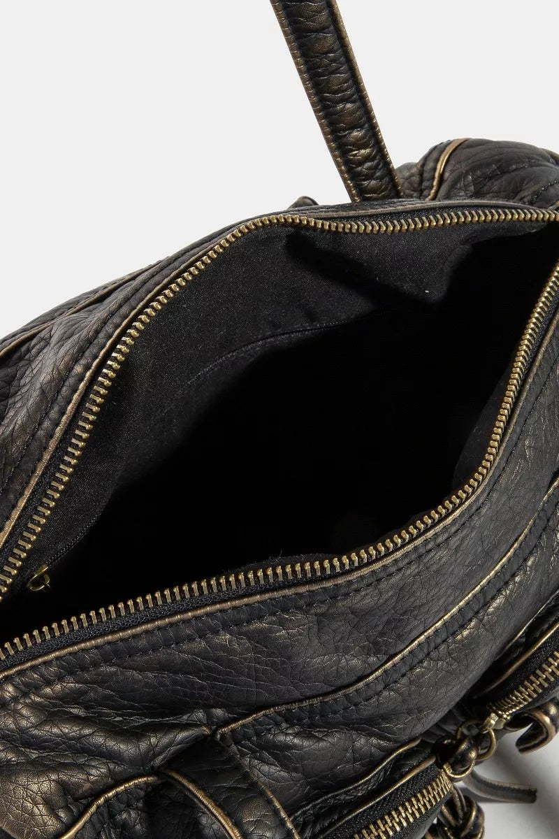 Close-up of a black leather bag with gold zipper details on a white background