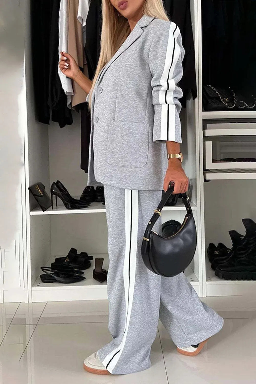 Woman in a gray outfit with white stripes standing in front of a wardrobe.
