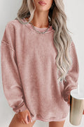 Person wearing a pink corduroy dress holding a white cup with a straw on a light background
