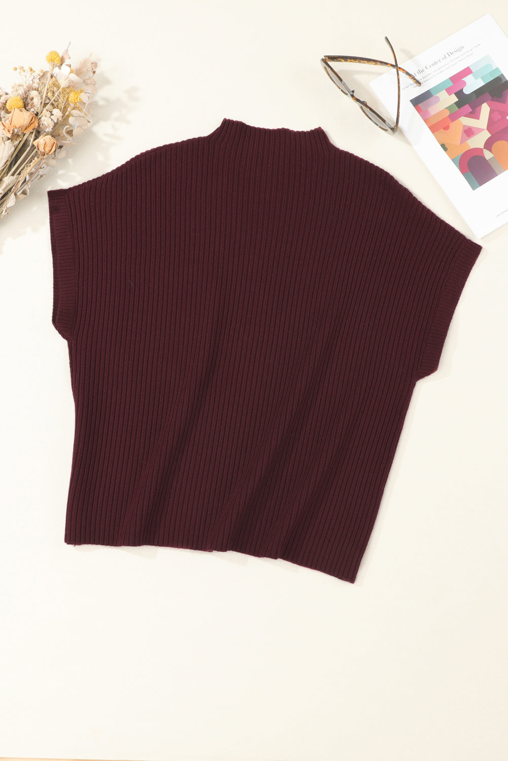Brown ribbed sweater vest on a white surface with decorative elements.