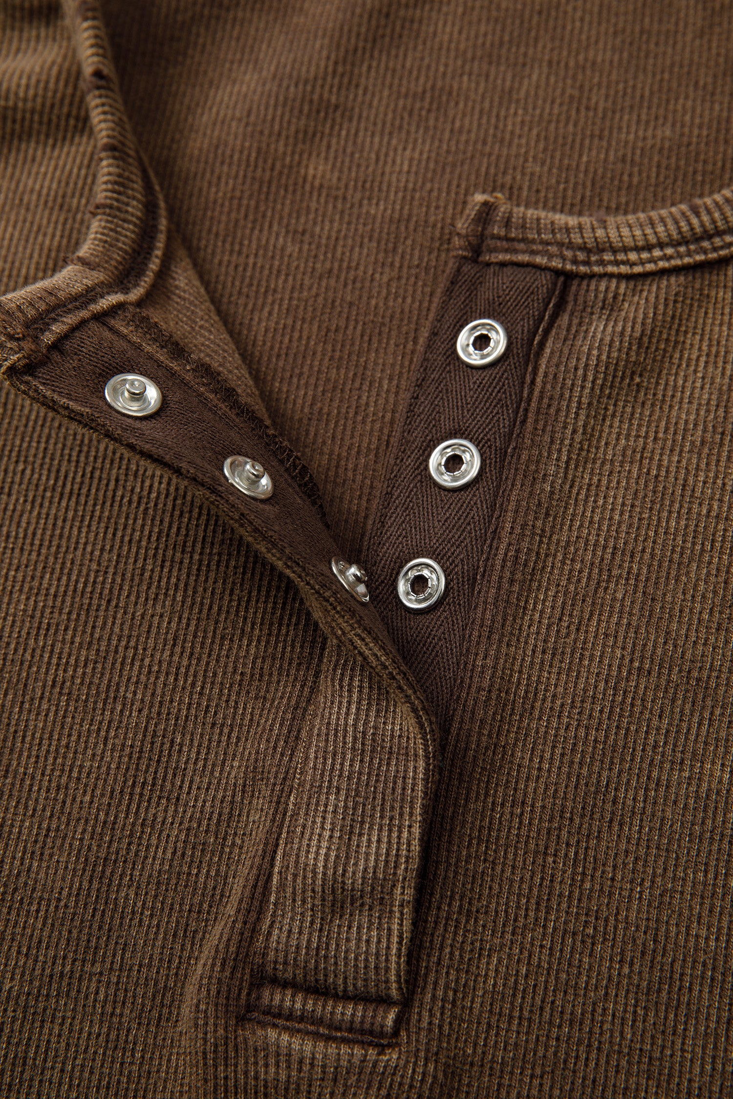Close-up of a brown corduroy tank top garment with button detailsk 