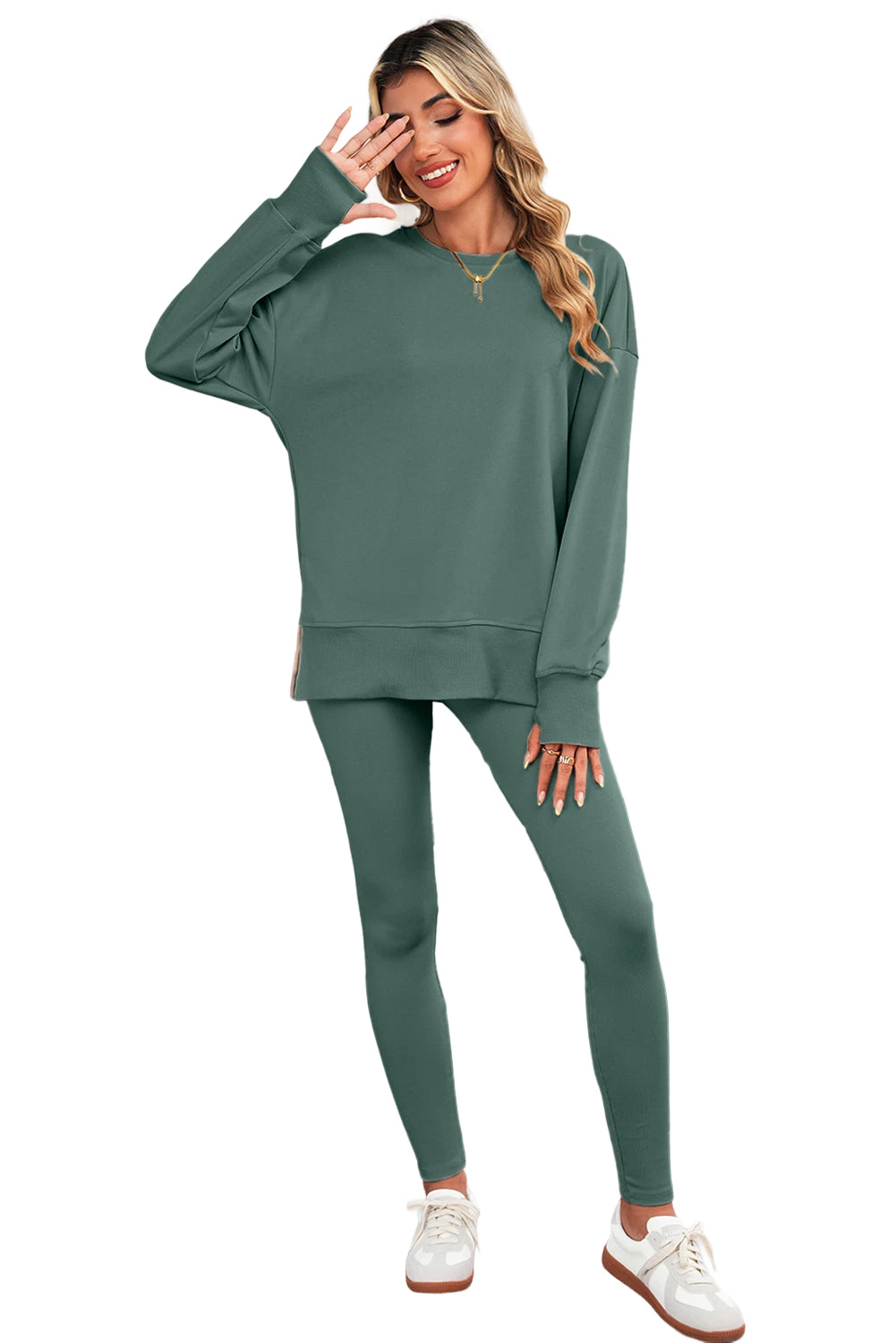 Woman wearing a green sweatshirt and leggings set on a white background