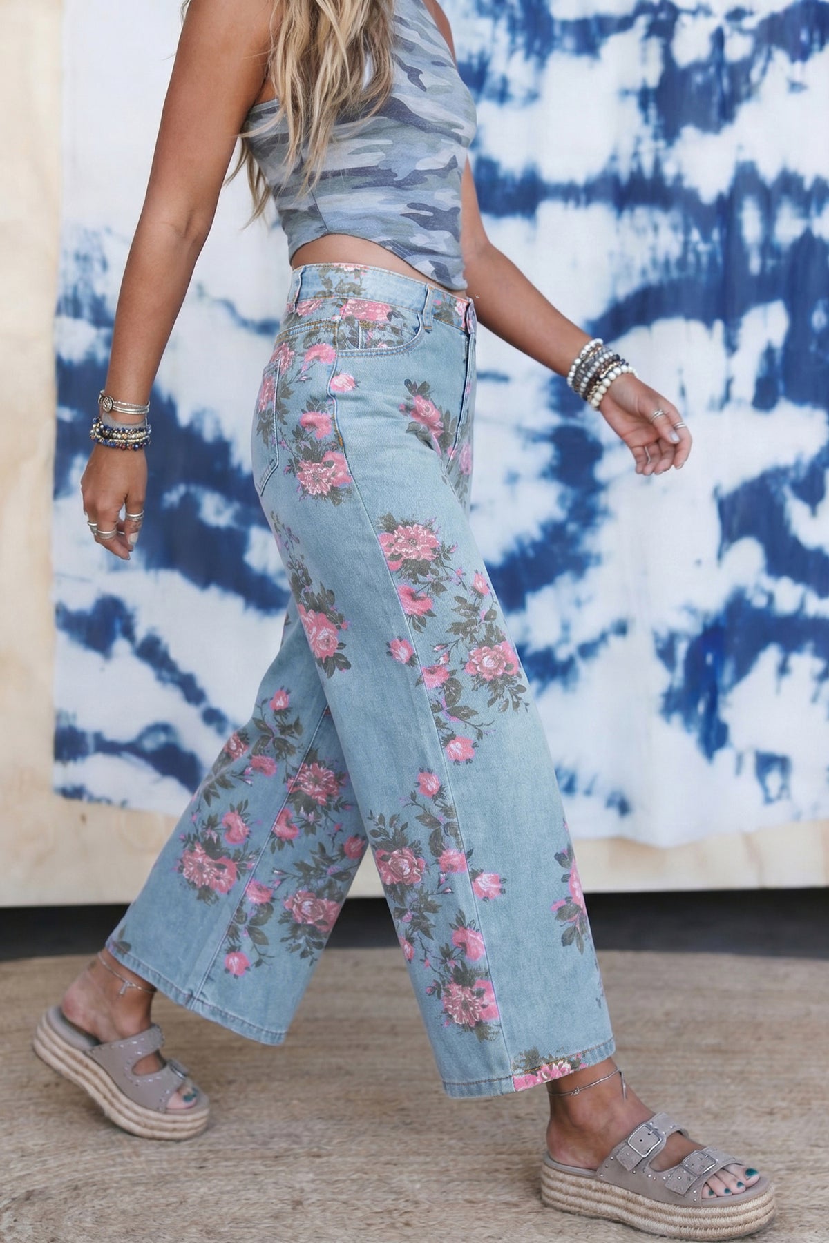 Person wearing a floral denim outfit with a tie-dye background side view