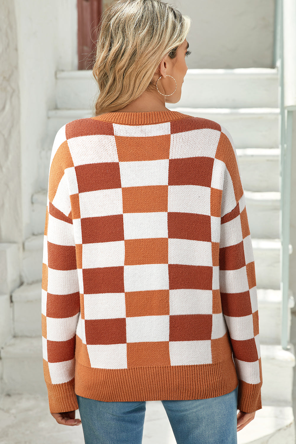 Person wearing a checkered sweater with orange and white pattern.