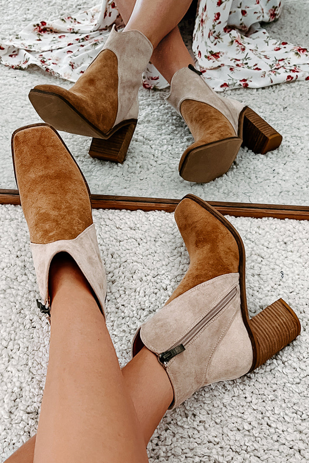Pair of brown and beige suede ankle boots on a textured white surface.