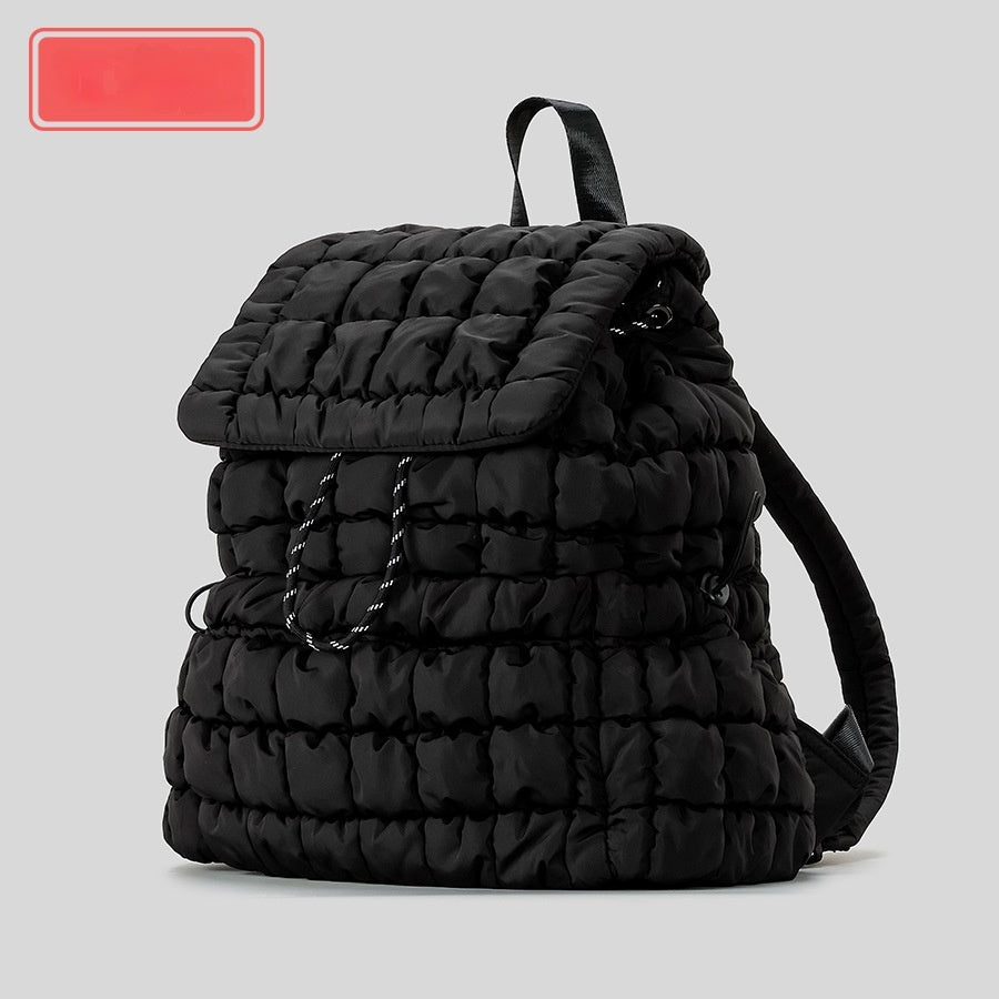Black quilted backpack on a light gray background
