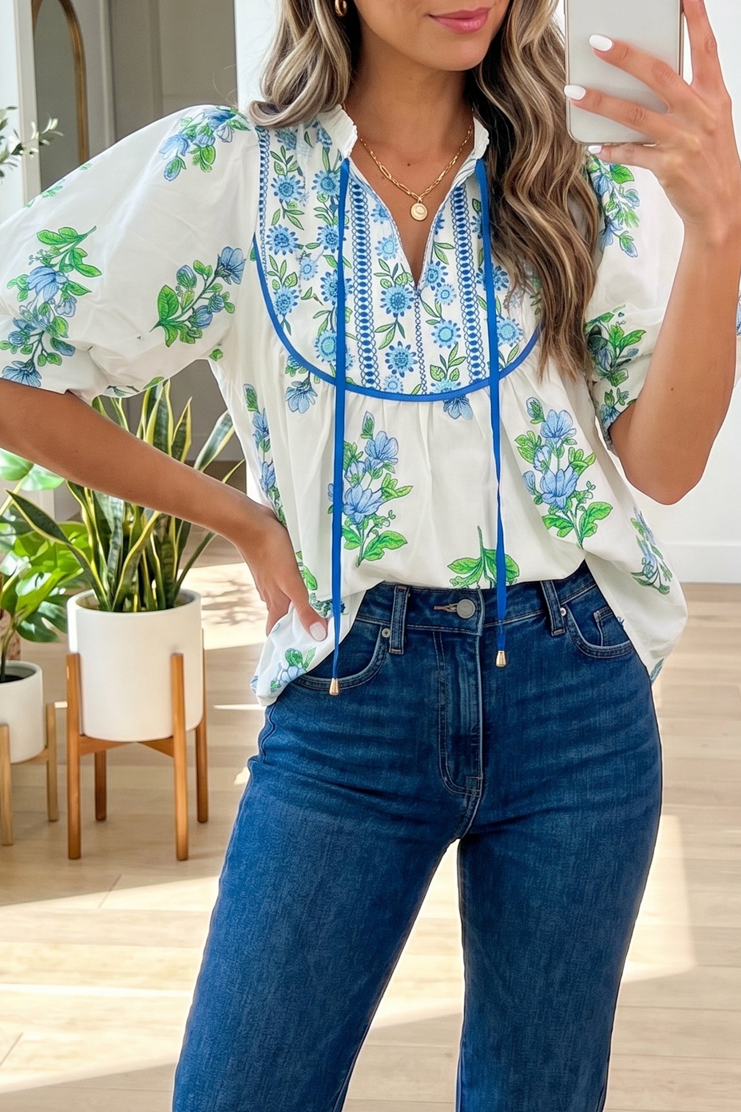 Woman wearing a floral blouse with blue accents and jeans indoors.