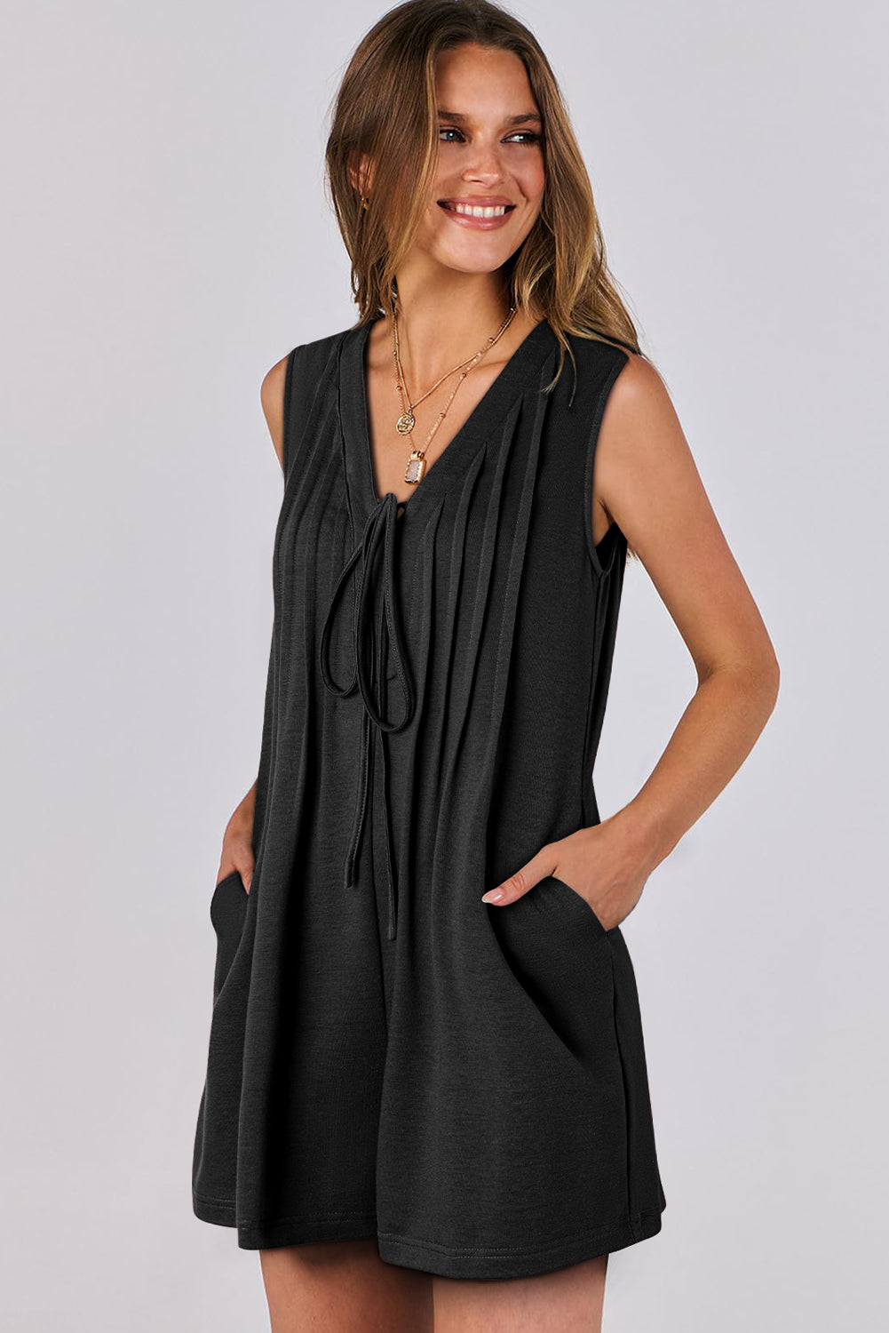 Woman wearing a black sleeveless dress against a plain background