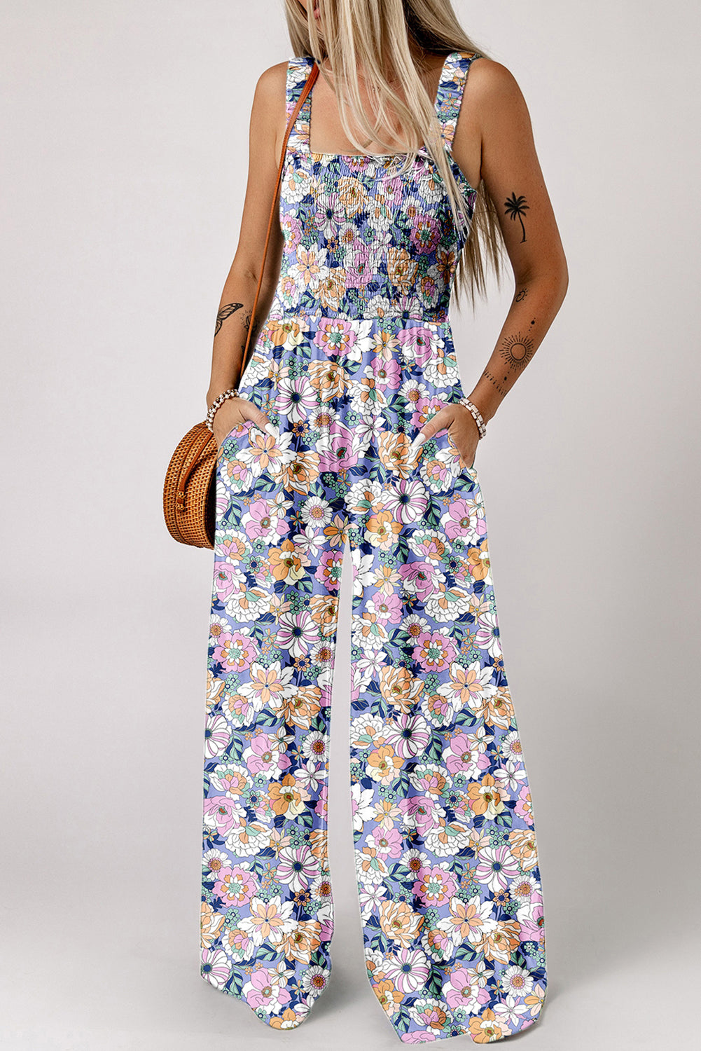 Woman wearing a floral jumpsuit on a plain background