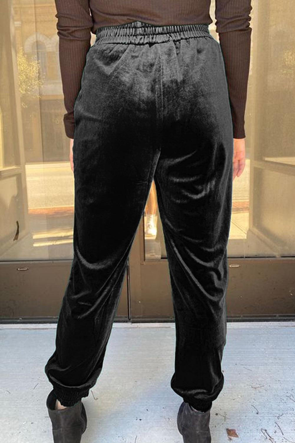 Person wearing black velvet pants with a blurred background
