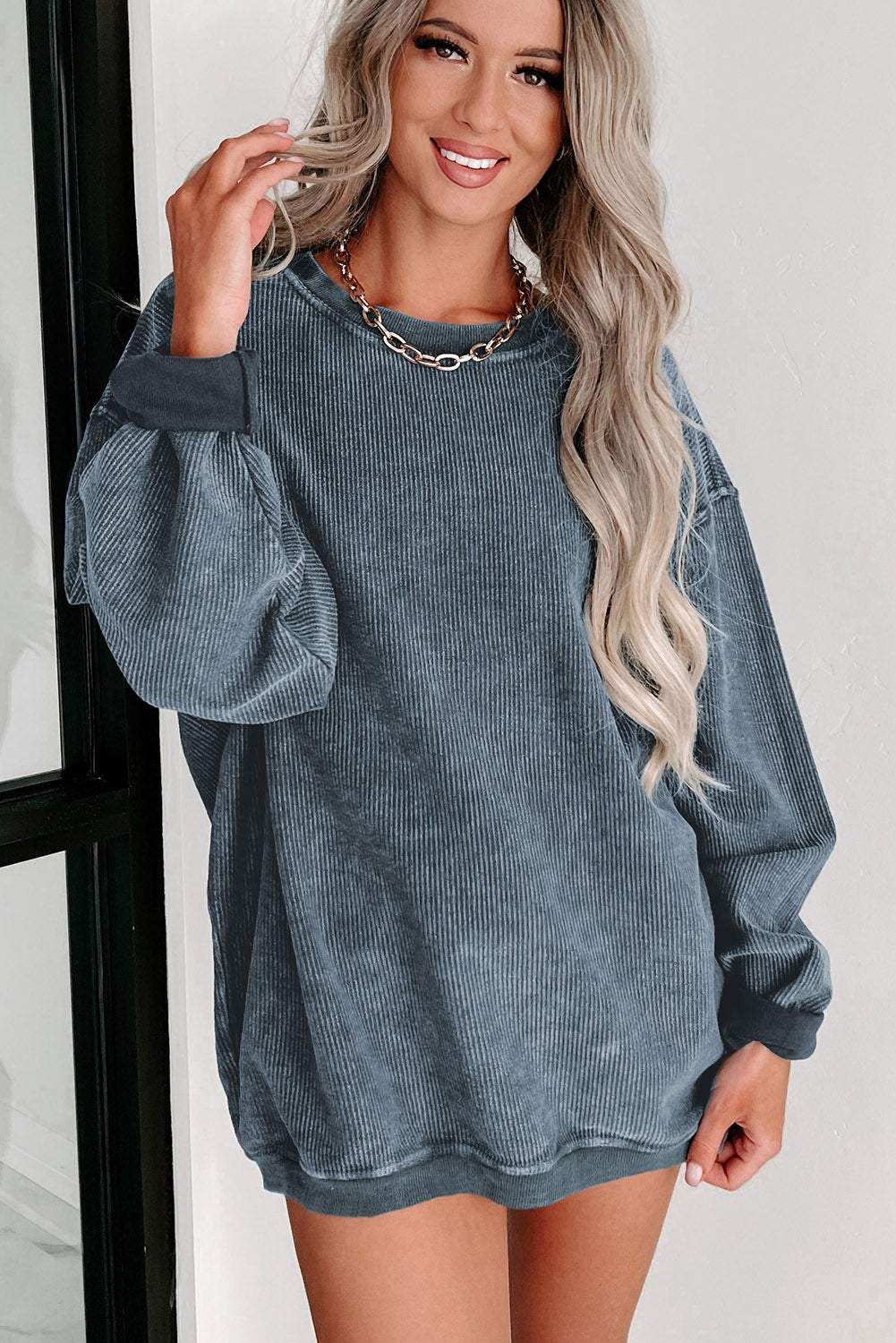Woman wearing a blue ribbed sweater dress against a white background