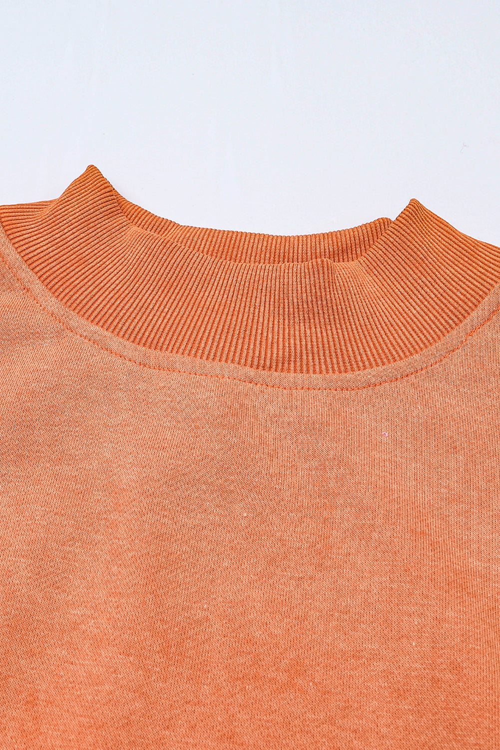Close-up of an orange sweater with a plain background