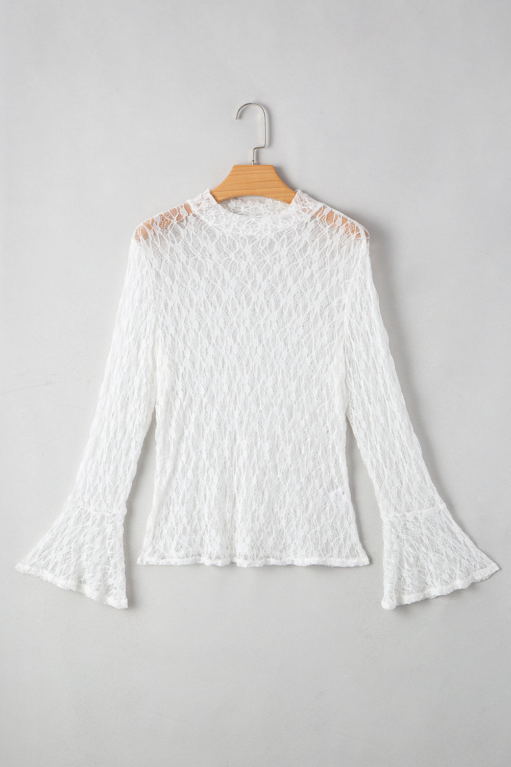 White lace blouse on a wooden hanger against a gray background