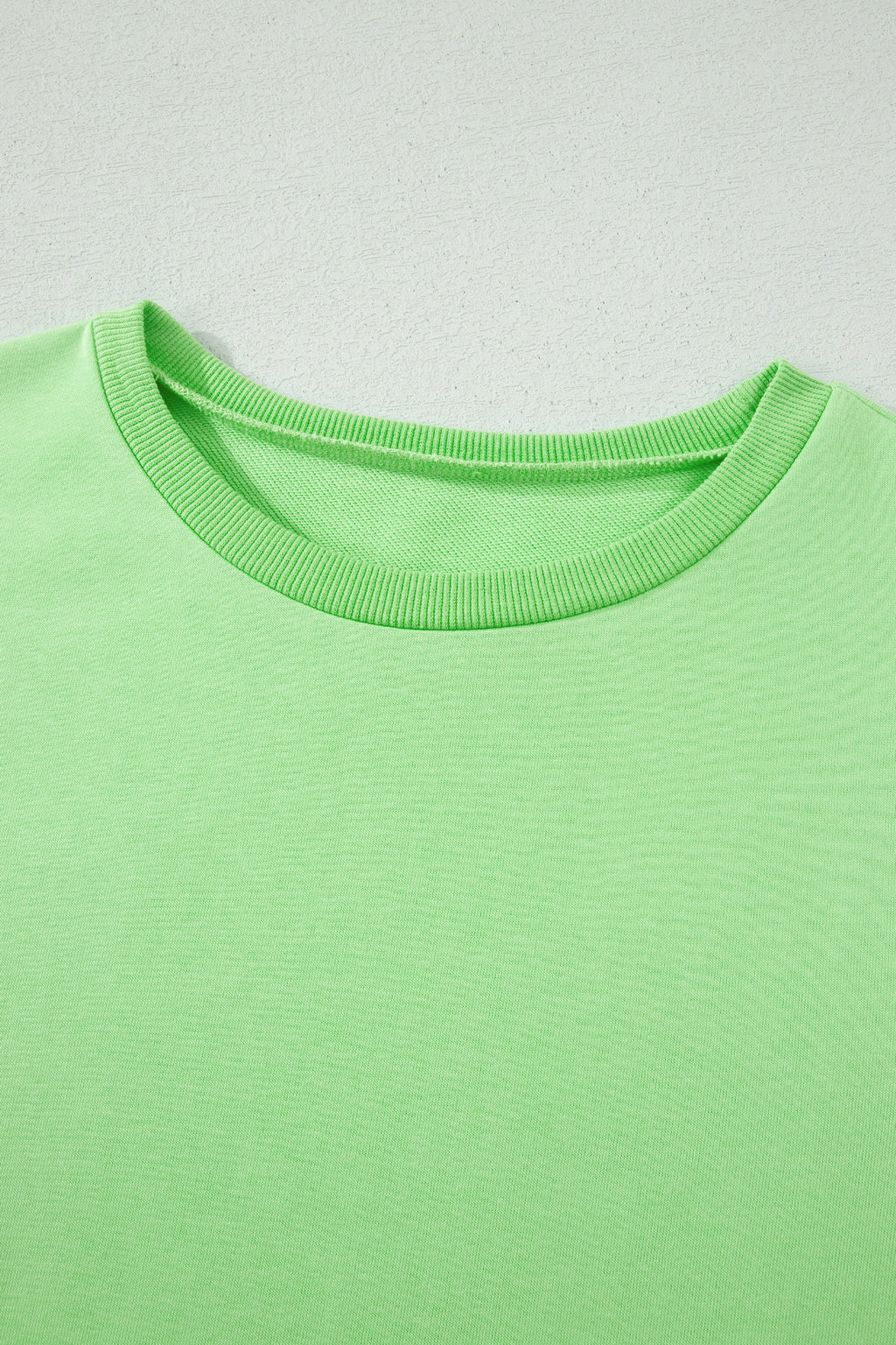 Close-up of a green shirt with a plain background
