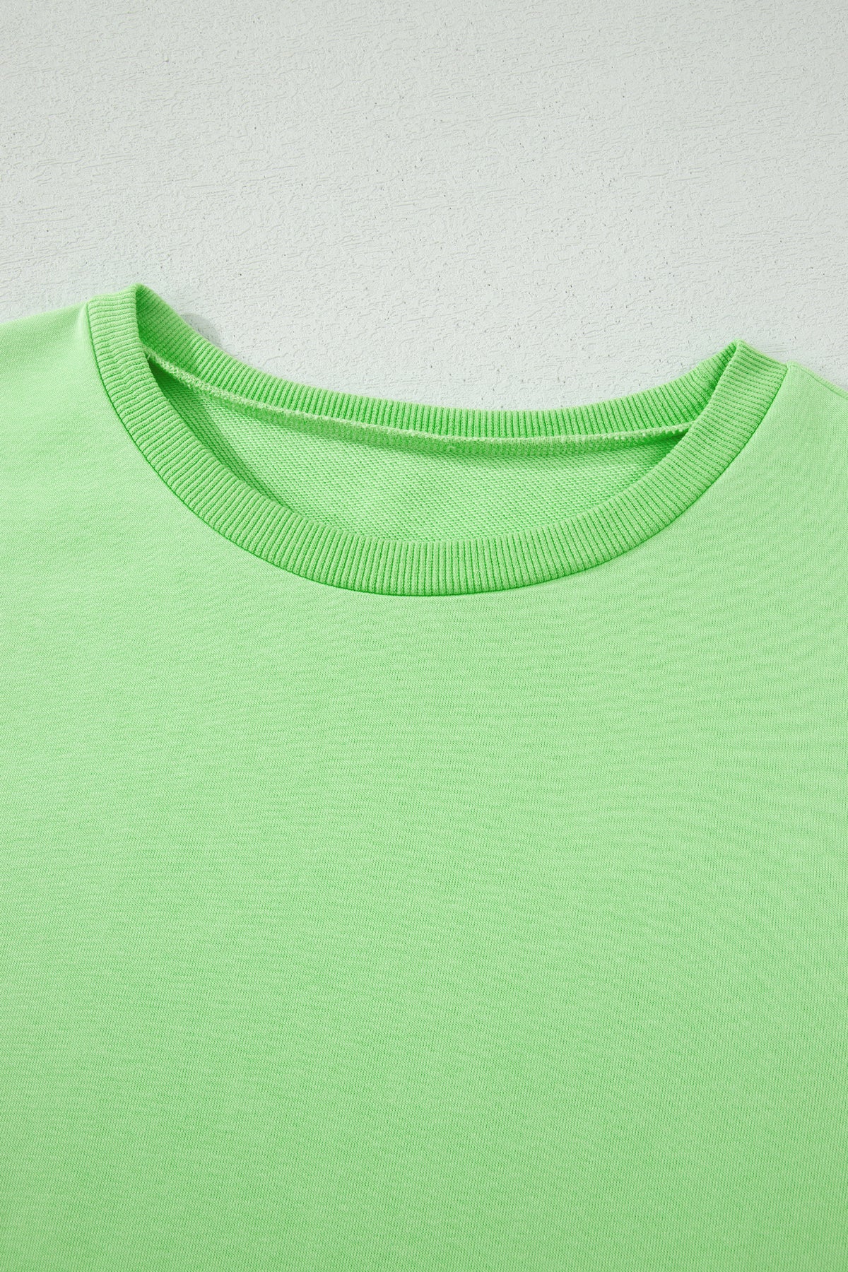 Close-up of a green shirt with a plain background