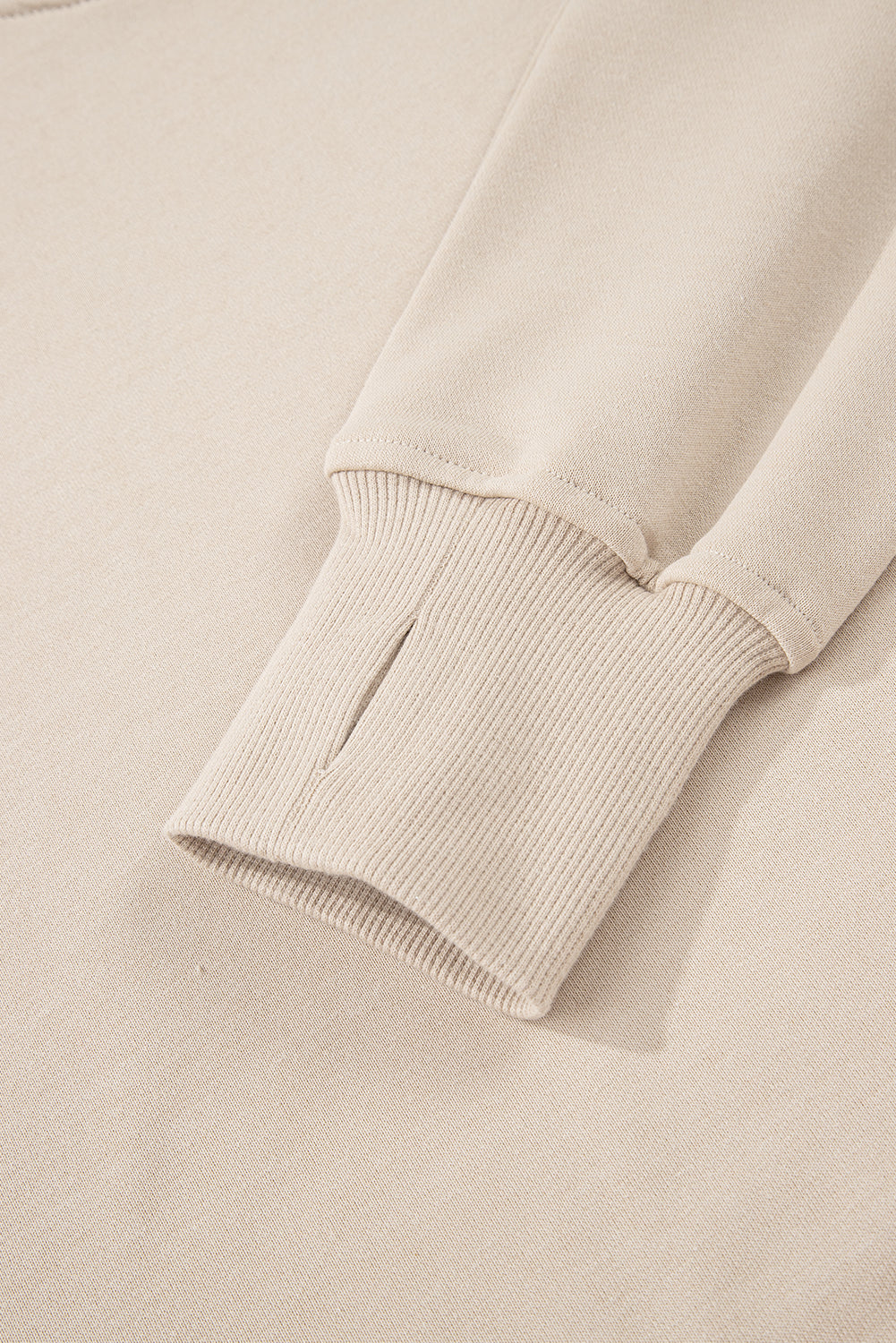 Close-up of a beige sweater sleeve on a matching background