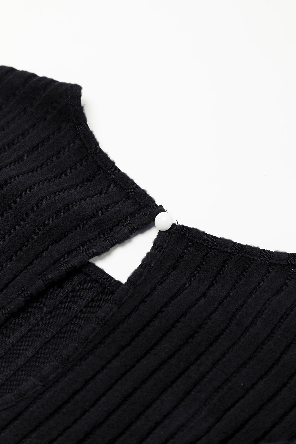Close-up of a black ribbed sweater with a white background