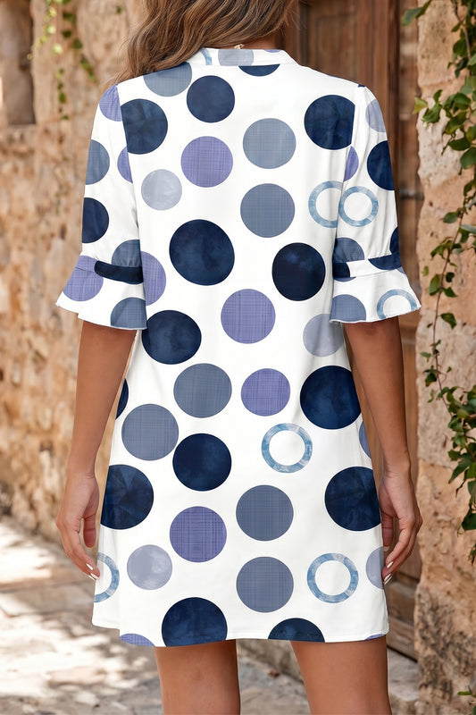 Woman wearing a polka dot blue dress with a neutral background back view