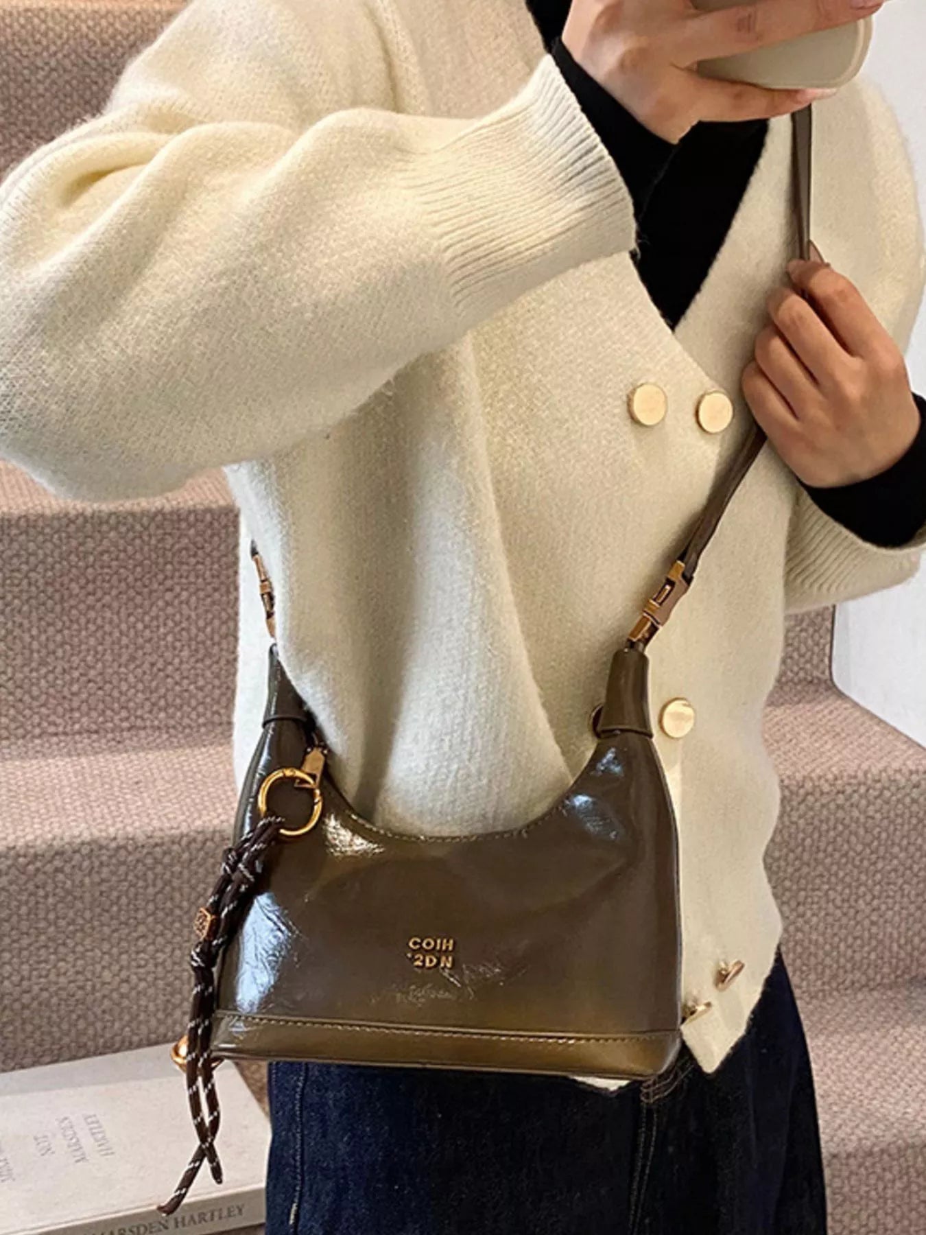 Person holding a brown leather handbag with visible branding