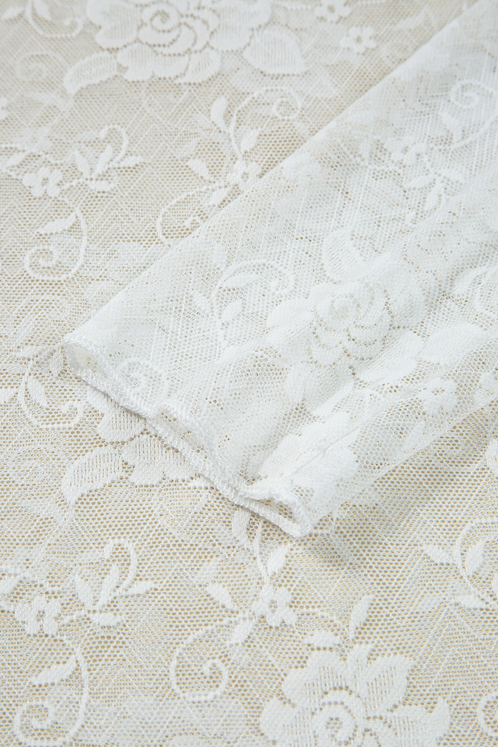 Close-up of white lace fabric on a textured beige background