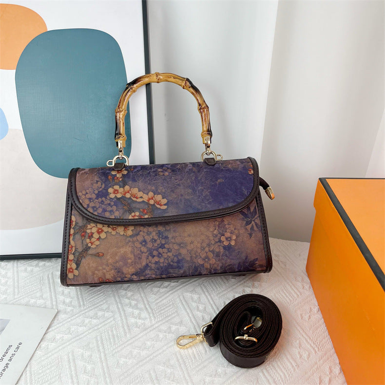 Floral patterned handbag with bamboo handle on a textured surface