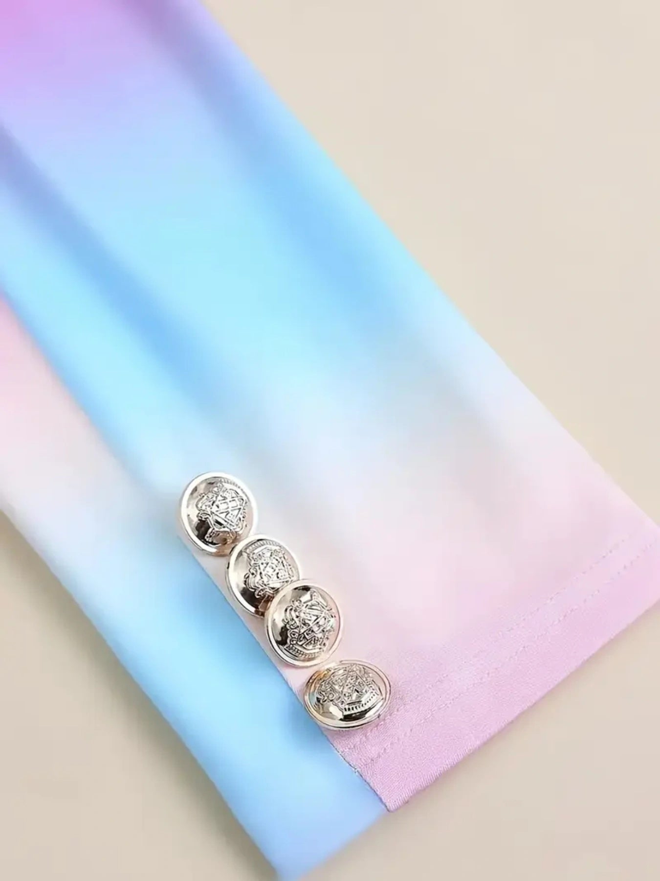 Gold earrings on a pastel gradient background