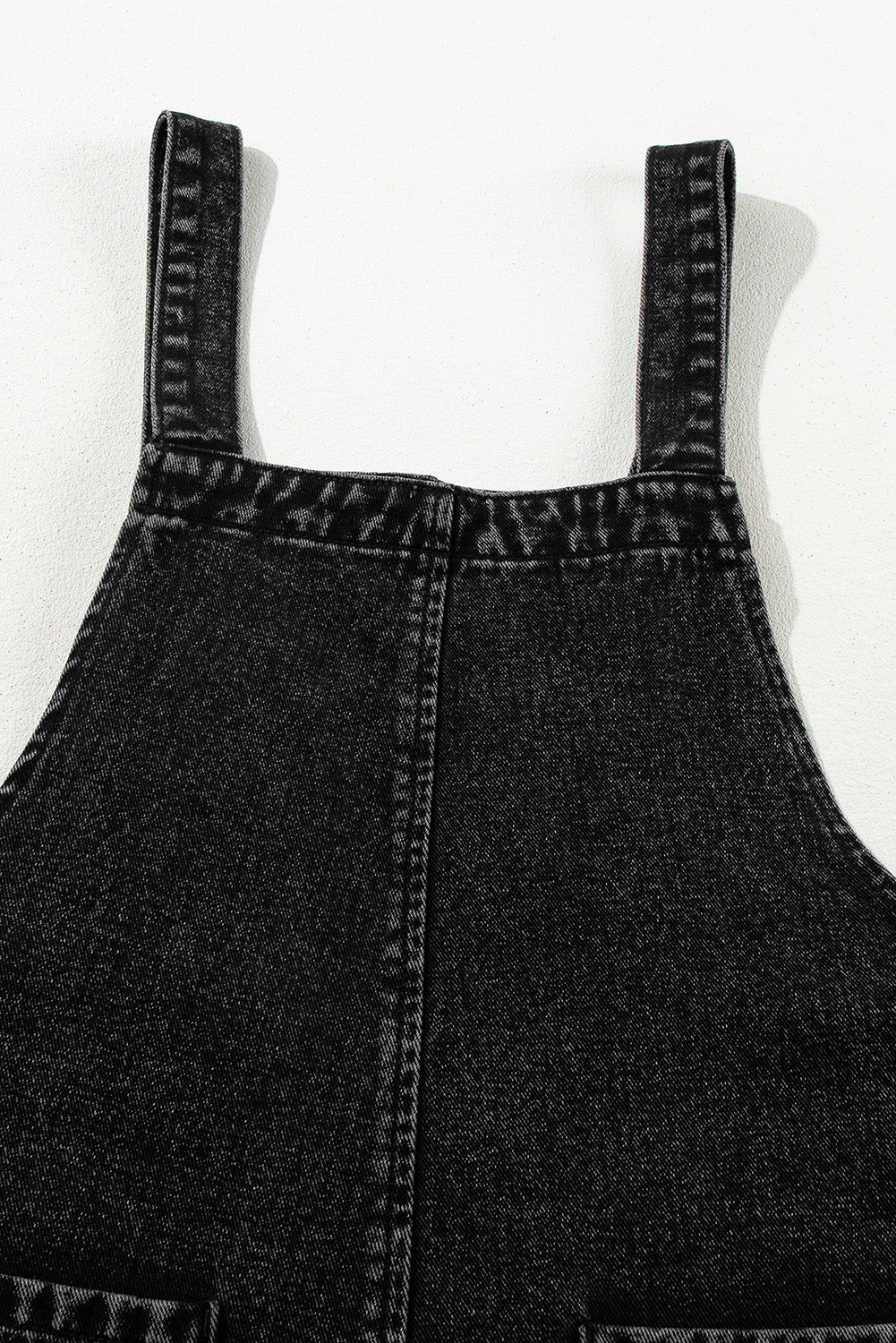 Black denim overalls on a white background