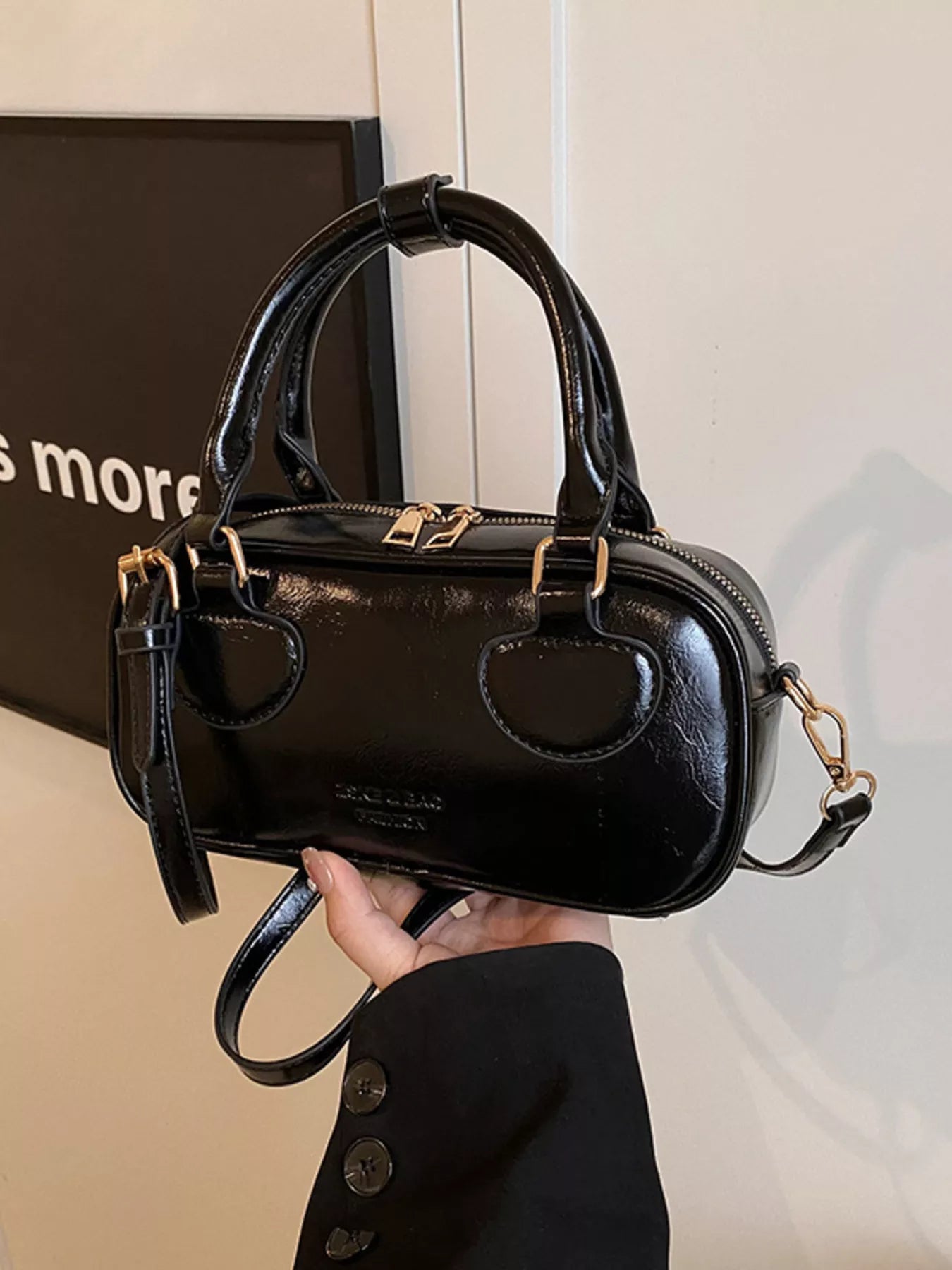 Black handbag held by a person with a blurred background