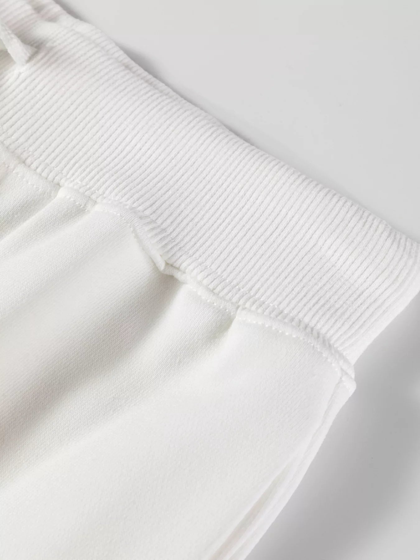 Close-up of a white sweatshirt with ribbed cuffs on a light gray background