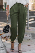 Person wearing green pants and a black handbag on a sidewalk.